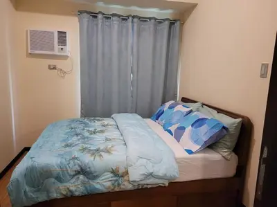 a bed with a blue comforter and pillows in a bedroom at The Radiance by Dominga in Manila