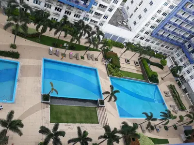 an overhead view of two large swimming pools with palm trees at 5 Years Legit Staycation Infront of Moa, Arena, Smx, Ikea, Sea Residences Tower A, Near Dfa Macapagal, Ayala Mall, World Trade, Naia123 in Manila
