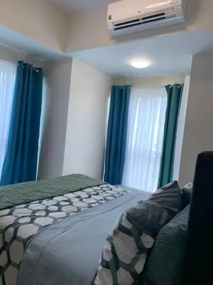 a bedroom with a bed with blue curtains and a fan at Le Maisse Executive Studio 1BR opp Okada in Manila