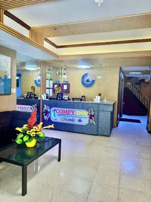 a lobby with a waiting area with a counter and a table at Comfy Inn Mabini Manila in Manila