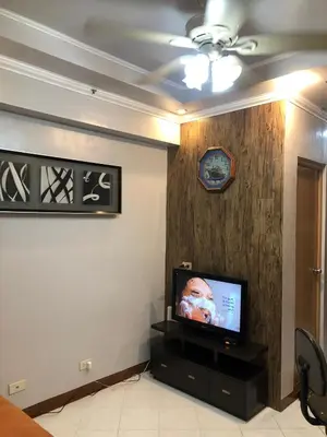 a living room with a tv and a wall with a clock at 2 separate fully furnished condo units 1BR on the 23rd flr and 3BR penthouse on the 41st flr, with different bookings and daily rates in Ermita, Manila near SLEC,US Embassy, Mall and Parks in Manila