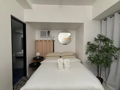 a bedroom with a large white bed with two pairs of shoes at 1BR Studio at viceroy McKinley taguig in Manila