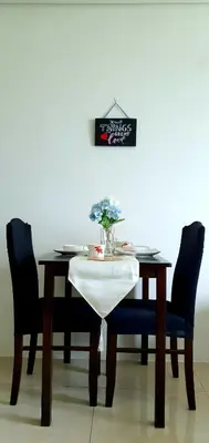a dining room table with two chairs and a table with a vase of flowers at LukeatSkye Suite - The Beacon Makati in Manila
