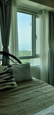 a bedroom with a bed with a large window at LukeatSkye Suite - The Beacon Makati in Manila