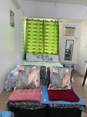 a bed with two pillows and a green window at Staycation budget room in Manila