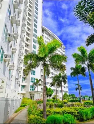 a tall building with palm trees in front of it at Staycation budget room in Manila