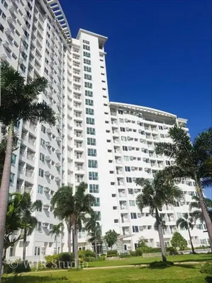 a large white building with palm trees in front of it at Staycation budget room in Manila