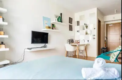 a bedroom with a bed and a desk and a television at Staycation in Manila (2 min. walk to Robinson's) in Manila