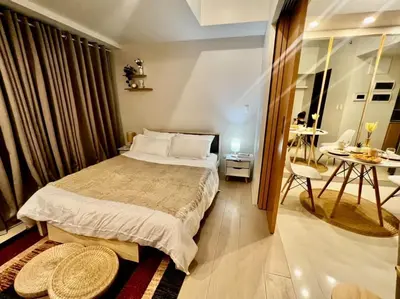 a bedroom with a bed and a table in a room at Lovely 1 Bedroom City View in Uptown BGC in Manila
