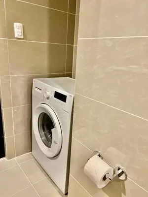 a washing machine in a bathroom with a roll of toilet paper at Lovely 1 Bedroom City View in Uptown BGC in Manila