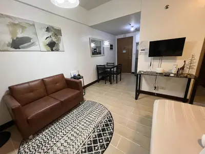 a living room with a couch and a television at 2 Palm Tree Villas - Manila Terminal 3 Airport Pasay in Manila