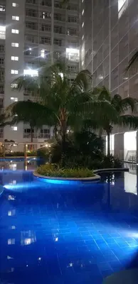 a large blue pool with palm trees and buildings at Jana@ShoreC2 in Manila