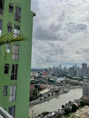 a green building next to a river and a city at U806 2Bedrooms PoolAccess Netflix wifi85mbps Karaoke in Manila