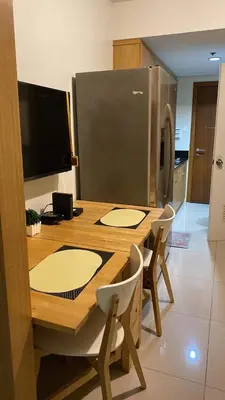 a kitchen with a wooden table with chairs and a refrigerator at SHELL RESIDENCE c7 shortwalk MALL OF ASIA in Manila