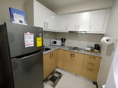 a small kitchen with white cabinets and a refrigerator at Uptown Parksuites Tower 1 BGC in Manila