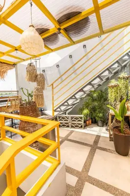 a patio with a yellow railing and potted plants at Rain Airport Bed and Breakfast in Manila