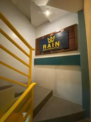 a sign on the wall of a room with stairs at Rain Airport Bed and Breakfast in Manila