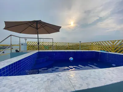 a blue tile swimming pool with an umbrella and a pool at Rain Airport Bed and Breakfast in Manila