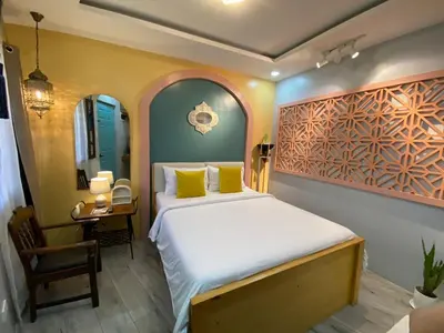 a bedroom with a bed with yellow pillows and a table at Rain Airport Bed and Breakfast in Manila