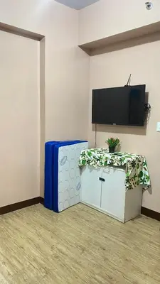 a room with a table and a tv on a wall at staycation affordable alabang in Manila