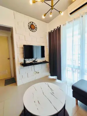 a living room with a table and a tv on a wall at Lyndon at Sea Residences, SMDC MOA Complex, Pasay City, Philippines in Manila
