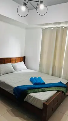 a bedroom with a bed with two blue pillows on it at Lyndon at Sea Residences, SMDC MOA Complex, Pasay City, Philippines in Manila