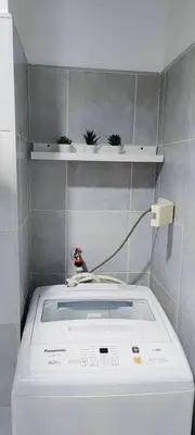 a washing machine in a bathroom with plants on a shelf at Lyndon at Sea Residences, SMDC MOA Complex, Pasay City, Philippines in Manila