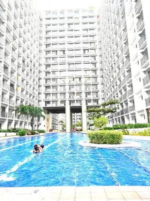 a person swimming in a swimming pool in front of a large building at Staycation by Janeil at Shore 2 Residences SMDC, MOA Complex, Pasay City, Philippines in Manila