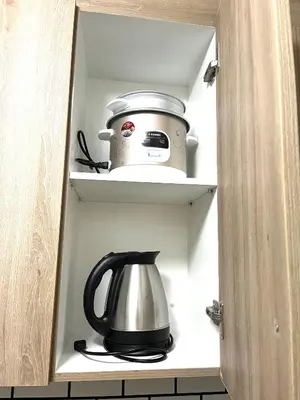 a tea kettle and a toaster sitting in a cabinet at Staycation by Janeil at Shore 2 Residences SMDC, MOA Complex, Pasay City, Philippines in Manila