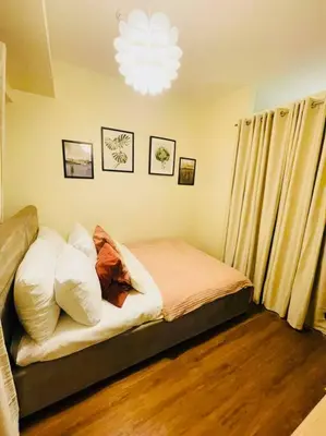 a bedroom with a bed with pillows and a chandelier at Stylish 1 bedroom condo with pool view and Fast WIFI in Manila