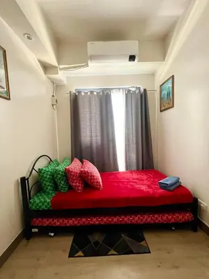 a bedroom with a red bed with a window at OneTiago Staycation - Spring Residences Paranaque in Manila