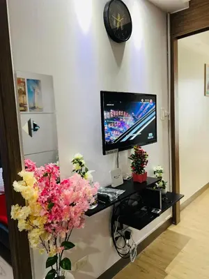 a room with a desk with a tv and flowers at OneTiago Staycation - Spring Residences Paranaque in Manila