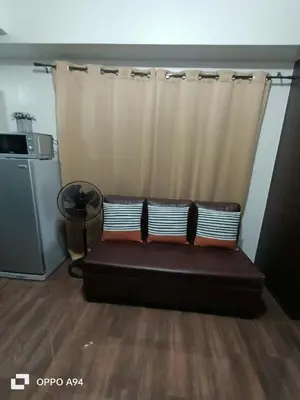 a couch in a living room with a curtain at Cruz Air Residences in Manila