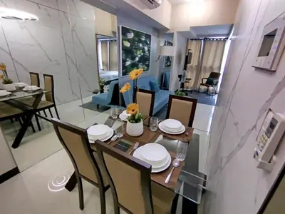 a dining room and living room with a table and chairs at Cozy 1BR UPTOWN PARKSUITES Tower1 BGC in Manila