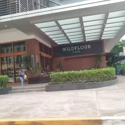 a woman walking in front of a building at Cozy 1BR UPTOWN PARKSUITES Tower1 BGC in Manila