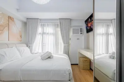 a bedroom with a large white bed and a mirror at The Radiance Manila Bay in Manila