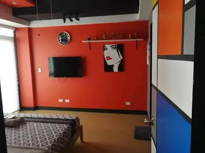 a room with a red wall with a bed and a tv at Cubao Manhattan Heights Unit 11PQ Tower B, 1BR in Manila