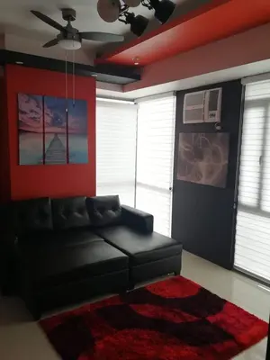 a living room with a black leather couch and a red wall at Cubao Manhattan Heights Unit 11PQ Tower B, 1BR in Manila