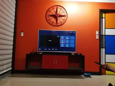 a tv on a stand with a clock on a wall at Cubao Manhattan Heights Unit 11PQ Tower B, 1BR in Manila