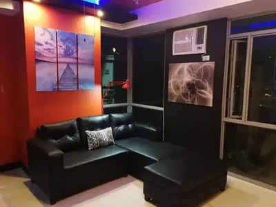 a living room with a black leather couch and a window at Cubao Manhattan Heights Unit 11PQ Tower B, 1BR in Manila