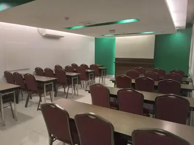 a room with tables and chairs and green walls at Go Hotels Otis - Manila in Manila