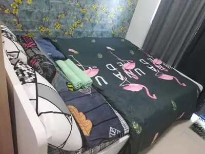 a bed with a green blanket with flamingos on it at Alatonplace sea residences in Manila