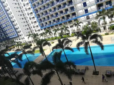 a large swimming pool with palm trees and buildings at Alatonplace sea residences in Manila