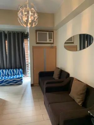 a living room with two couches and a mirror at MRMCONDOTEL cluster 1 2H in Manila