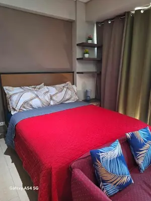 a bedroom with a bed with a red comforter at MRMCONDOTEL cluster 1 2H in Manila