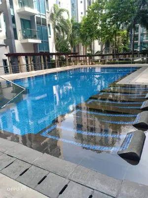 a blue swimming pool with stairs in a building at MRMCONDOTEL in Manila