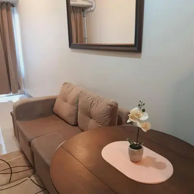 a living room with a couch and a table with a flower on it at SMDC Coast Residences Lovely Fully-furnished 1 BR Condo with pool in Manila