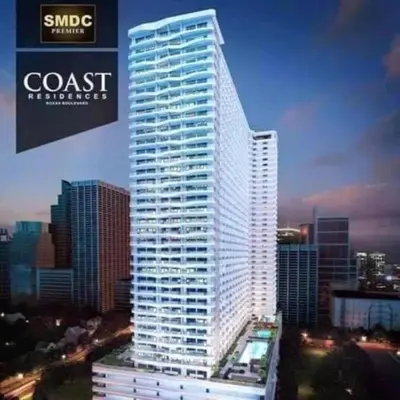a tall white building in front of a city at SMDC Coast Residences Lovely Fully-furnished 1 BR Condo with pool in Manila
