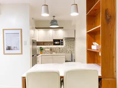 a kitchen and dining room with a white table and chairs at Large 1-Bedroom Condo 60sqm Makati Rockwell CBD Poblacion in Manila