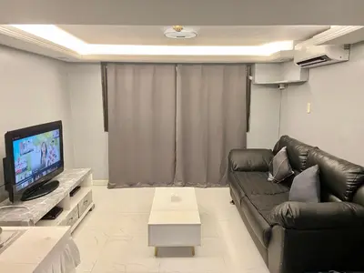 a living room with a black leather couch and a television at IV’s Condo w/ Netflix, Wifi & Karaoke in Cainta